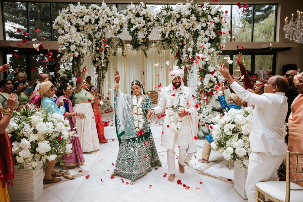 Joyful South Asian wedding at Lucien's Manor in Berlin, NJ, with the couple walking the aisle under a floral mandap and rose petal shower.