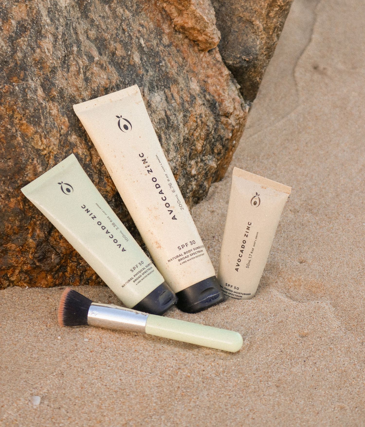 Collection of natural skincare products displayed on textured stone surface.