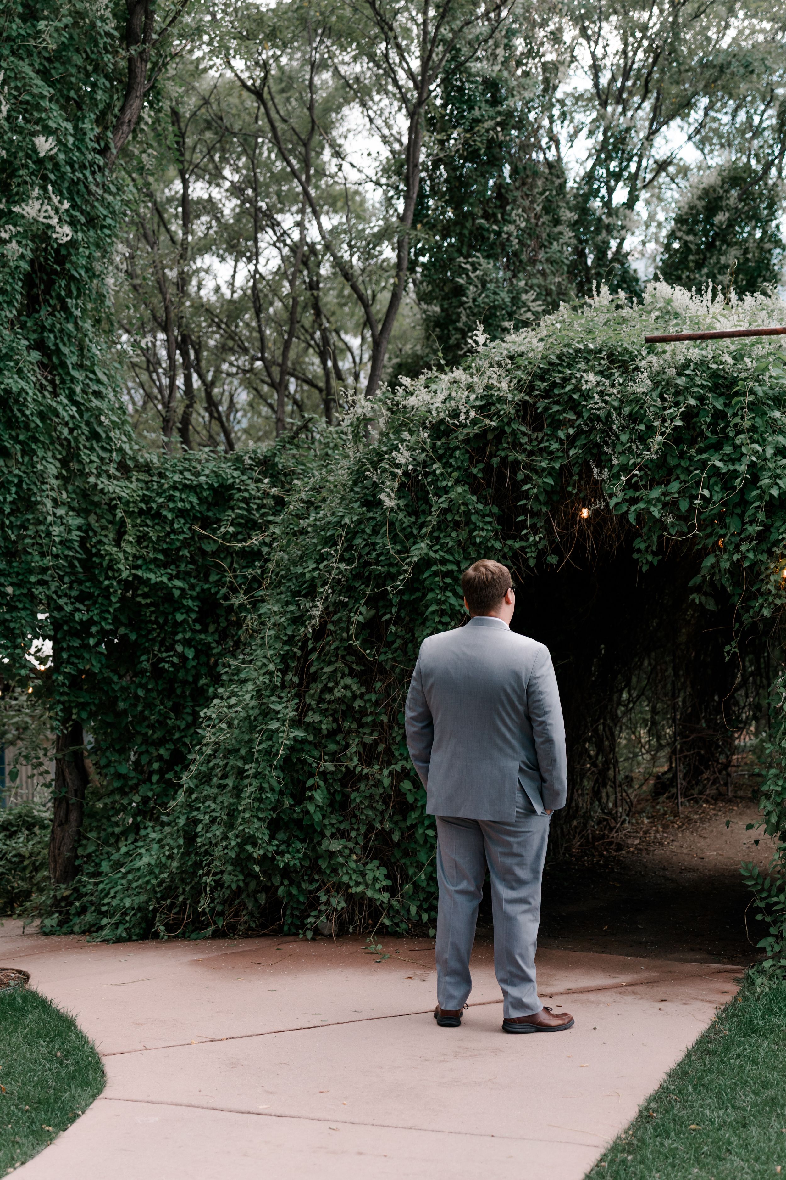 A sequence showing a person in a gray suit walking down a garden path surrounded by lush greenery.