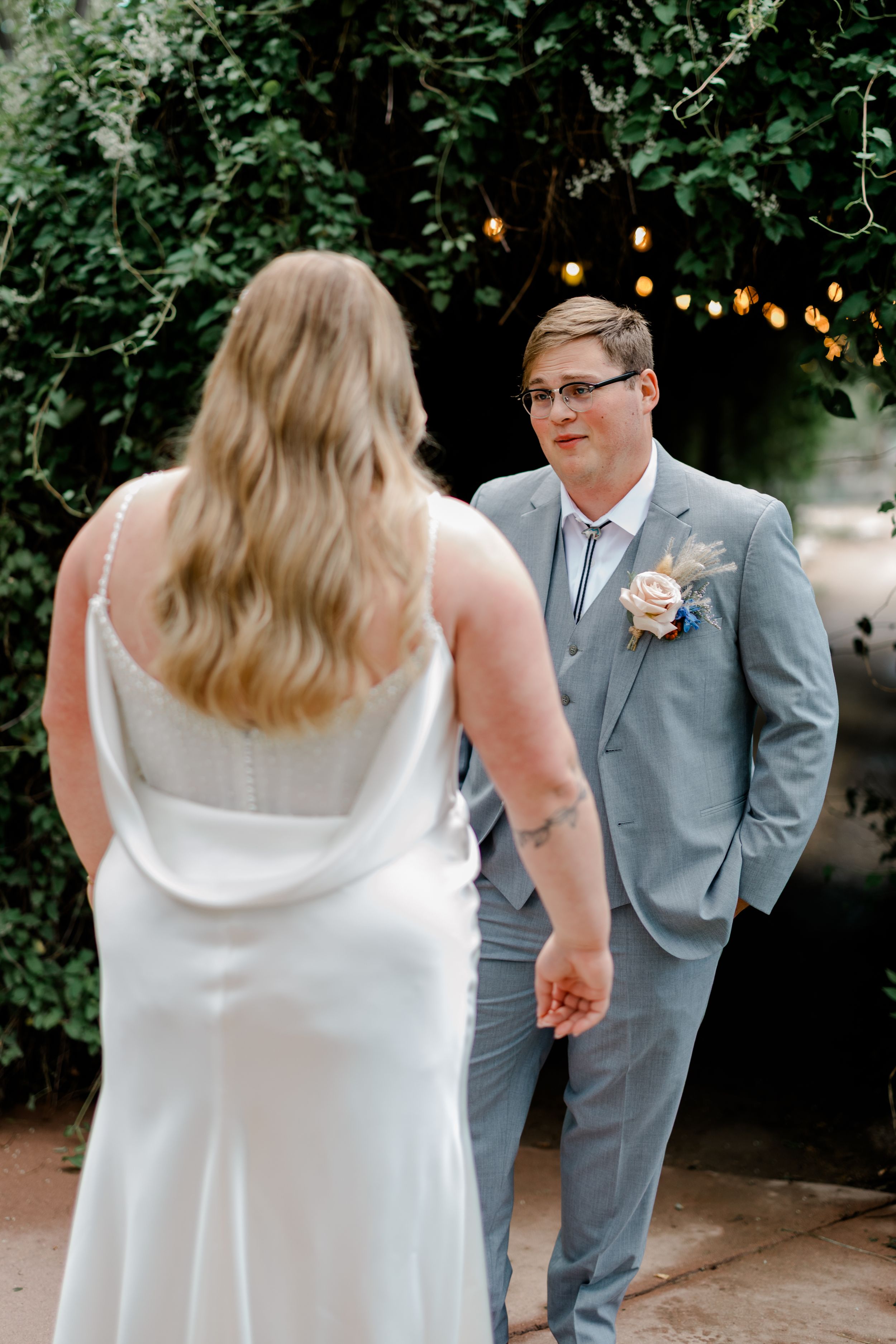 A couple shares their first dance at an outdoor wedding reception under string lights and trees.
