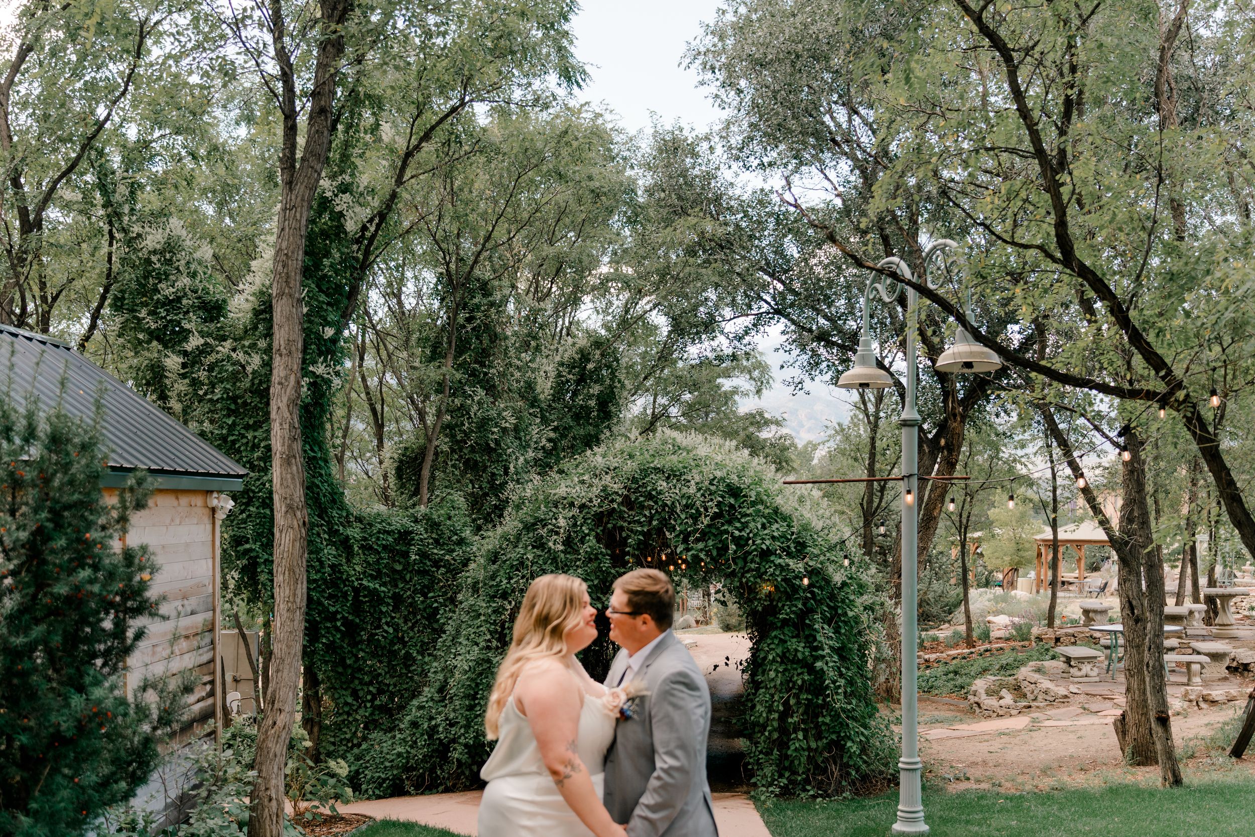 Wedding couple poses together on a scenic garden path with trees in the background.