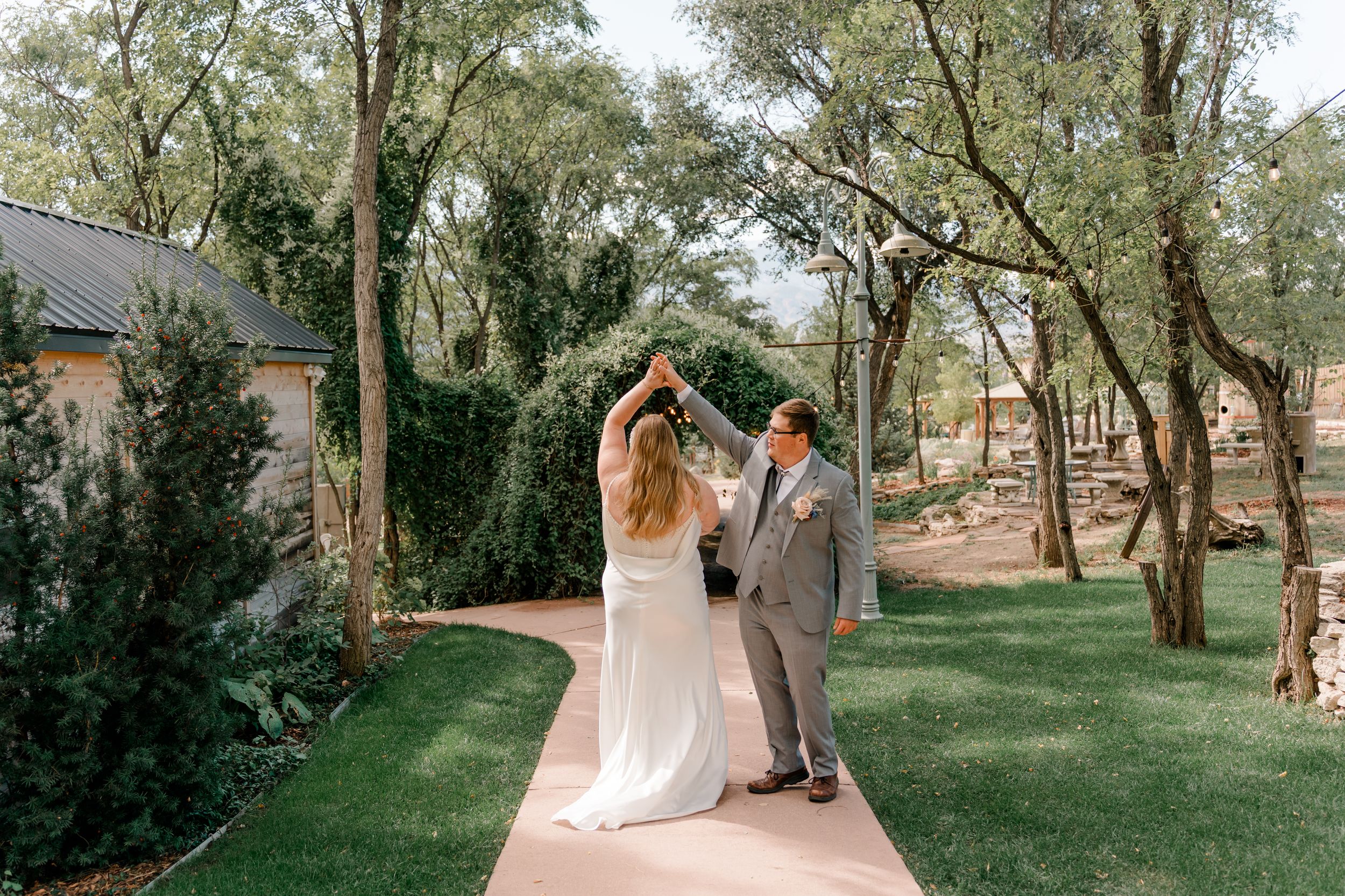 A romantic outdoor wedding scene with trees and sunlight filtering through the branches in a natural setting.