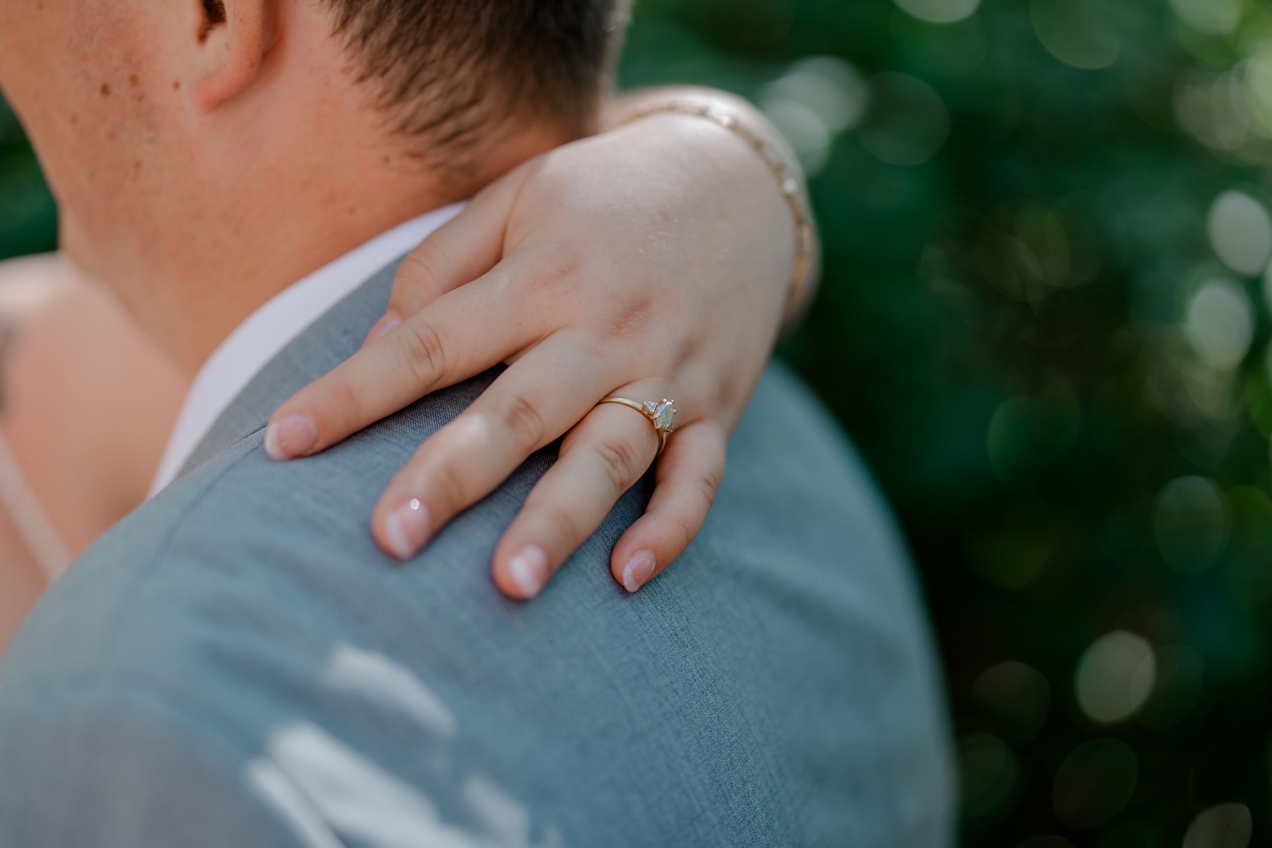 A couple embraces during a romantic outdoor photo session with soft bokeh lighting in the background.