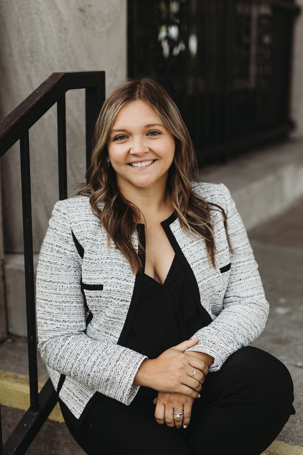 Professional headshots showing someone in a black and white tweed blazer sitting against an urban background.