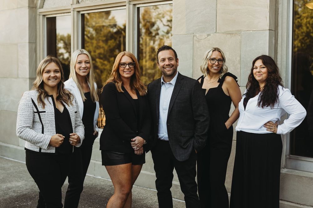 Professional group photo of colleagues in business attire standing together outside an office building.