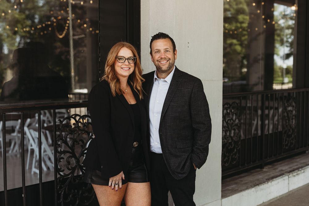 A couple in formal attire poses together outdoors during a professional photoshoot.