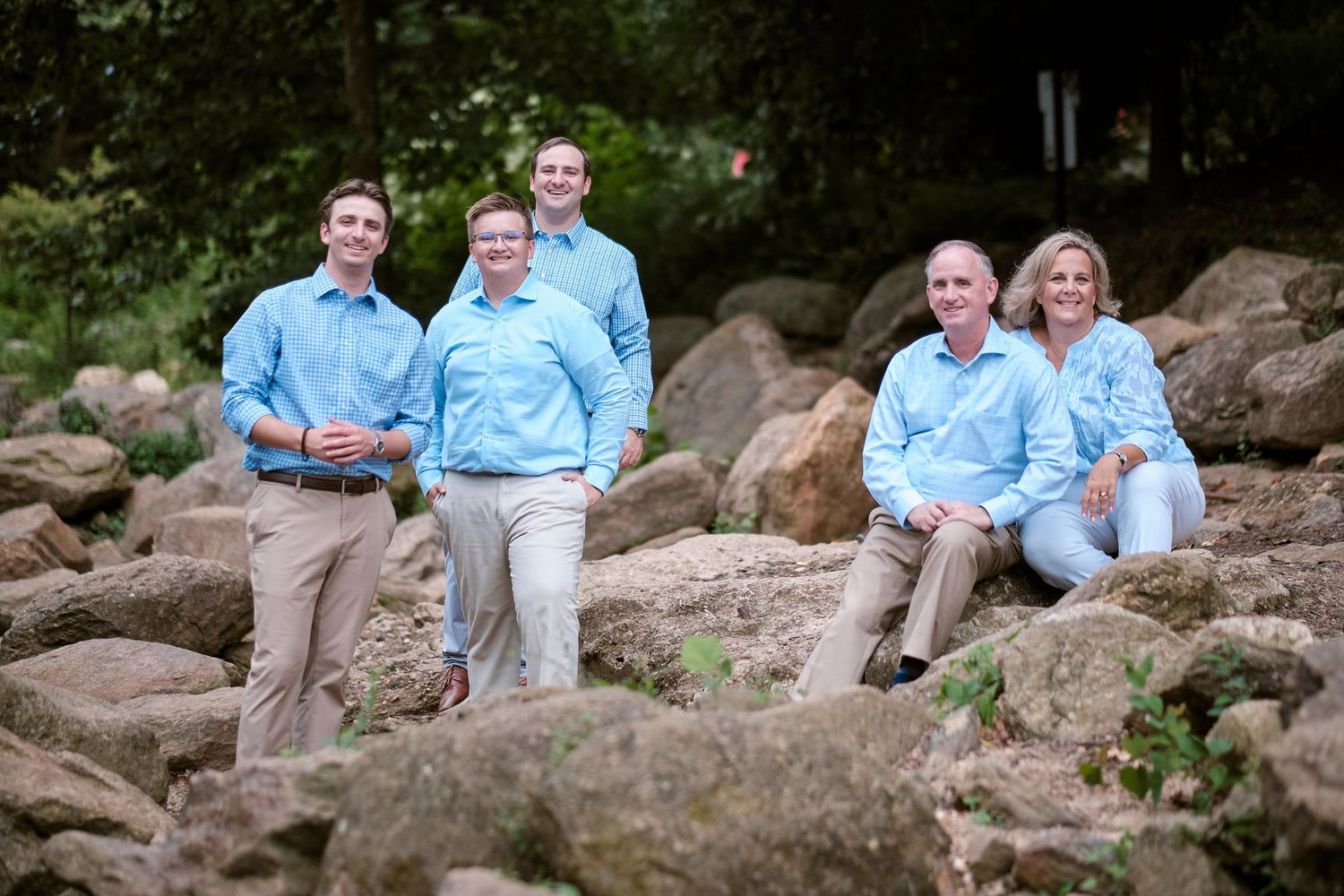 Two people sit together on large rocks in a natural outdoor setting wearing light blue and white clothing.
