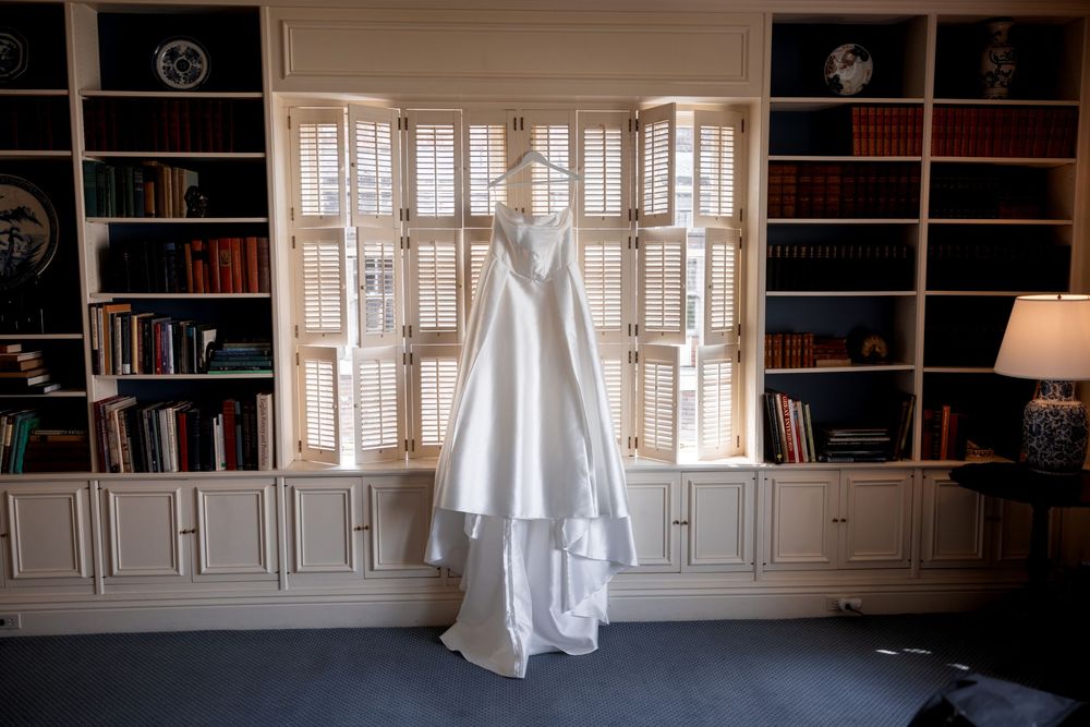 Empty room with built-in white bookshelves, windows, and a wedding dress displayed.