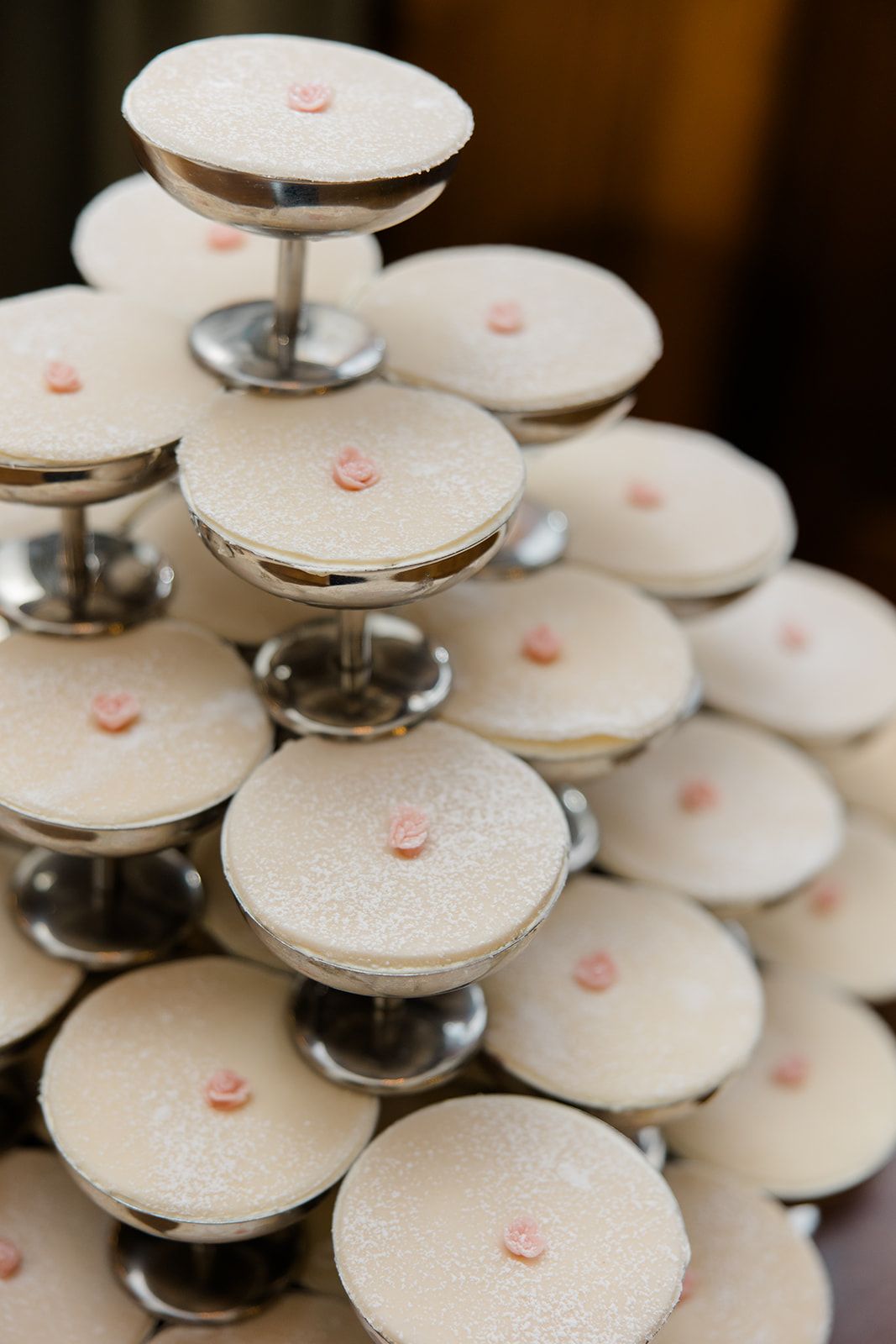 Tiered display of elegant white macarons with dark chocolate filling arranged on a dessert stand.