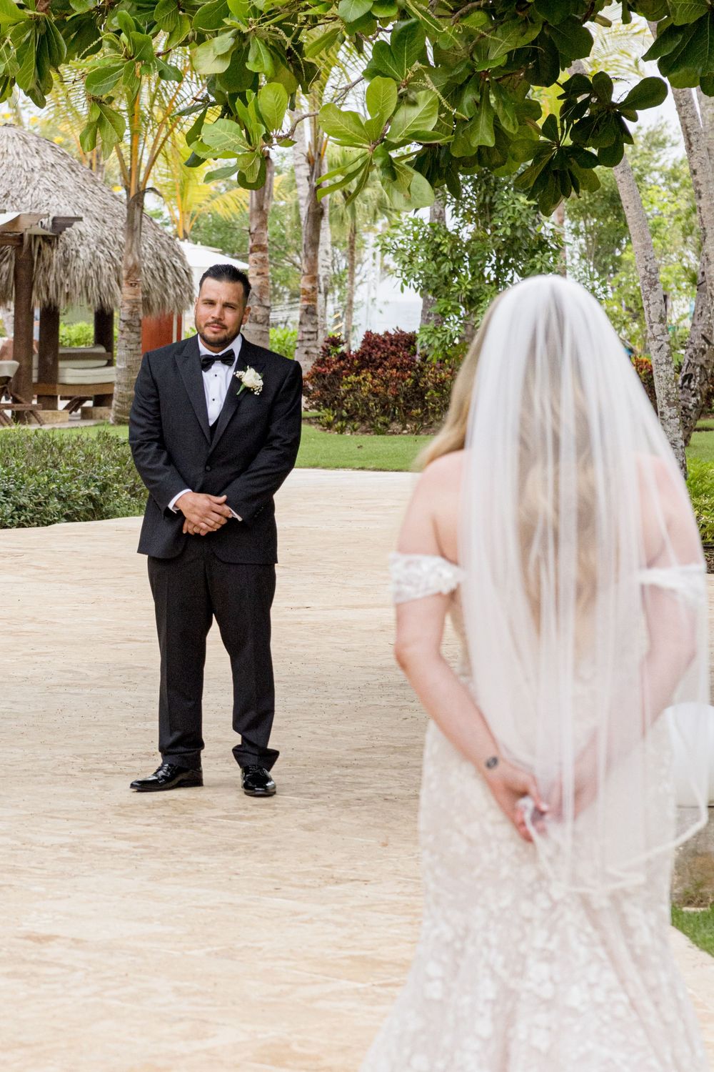 A romantic first look moment captured between a bride and groom in a lush tropical garden setting.