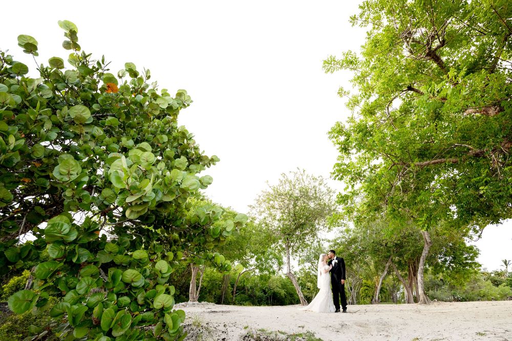 A wedding couple stands on a scenic cliff overlooking a natural landscape during an outdoor ceremony.