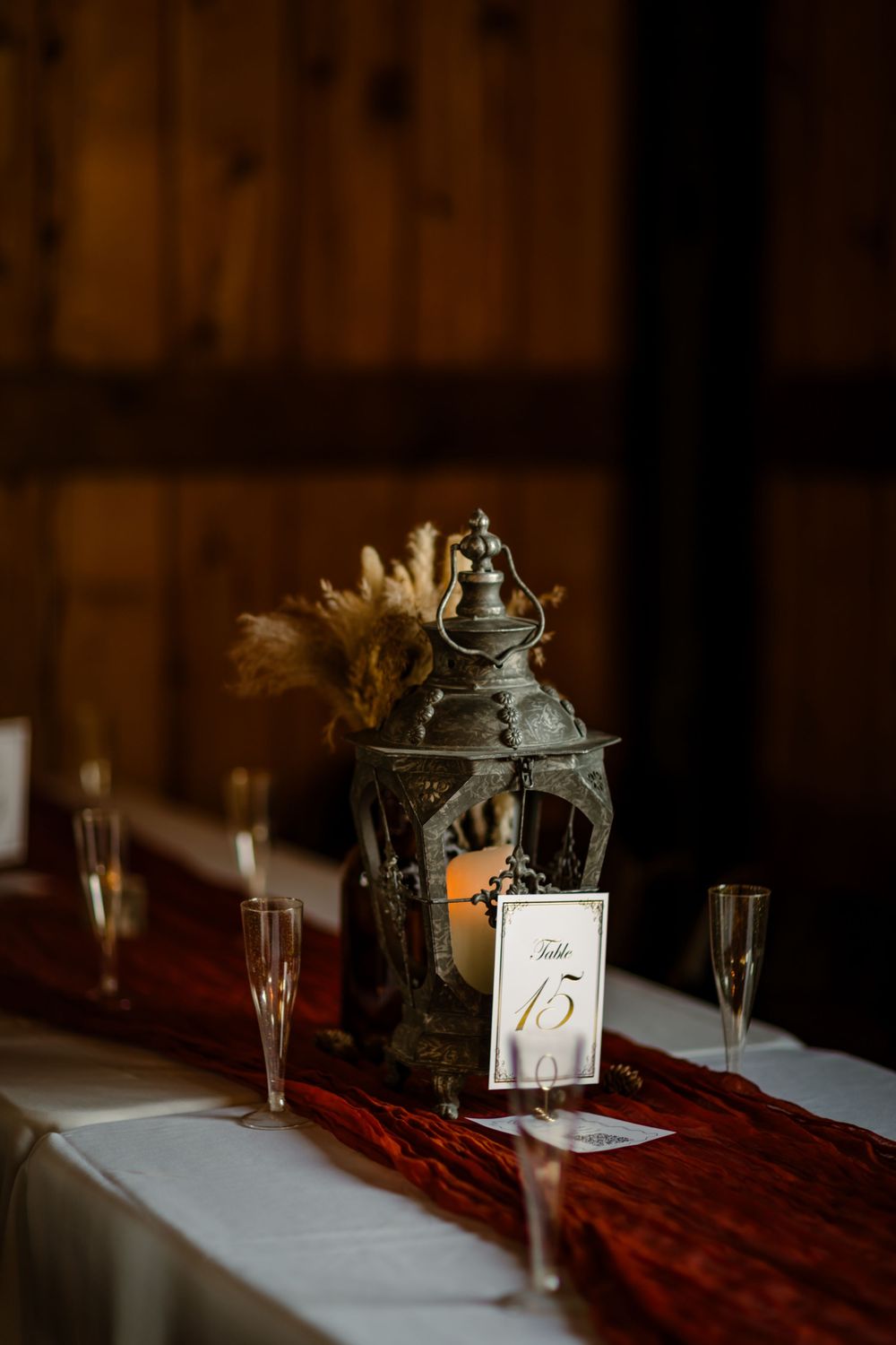 Vintage lantern centerpieces with table numbers and champagne glasses on red table runners.