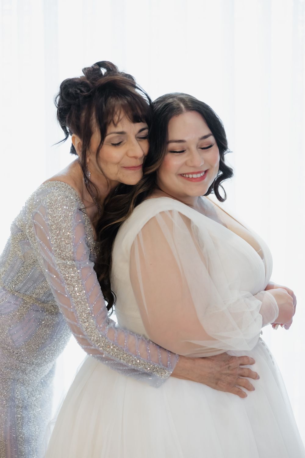 Two people sharing an intimate embrace in formal attire against a white backdrop.