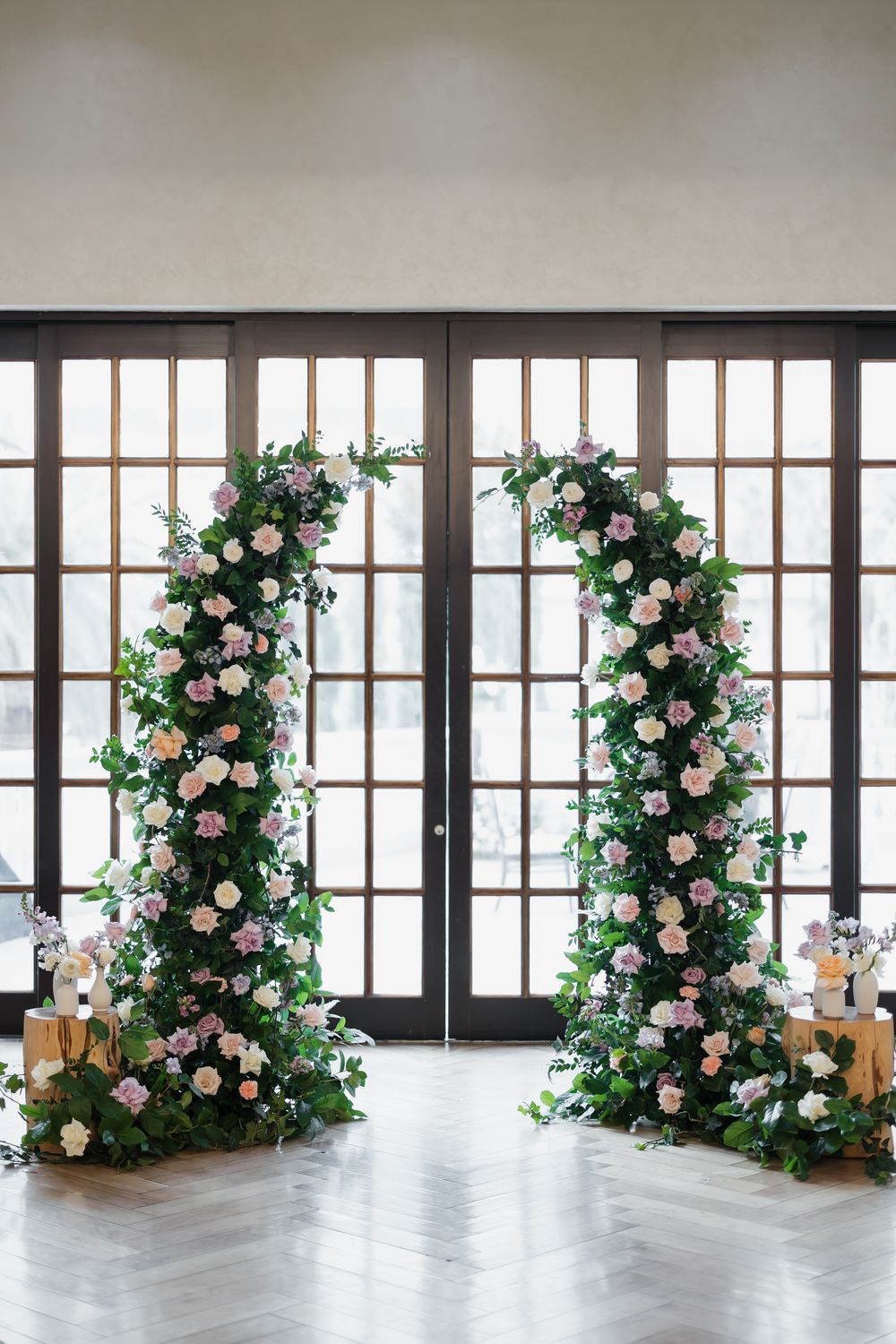 Wedding ceremony space with floor-to-ceiling windows and romantic floral pillar arrangements.