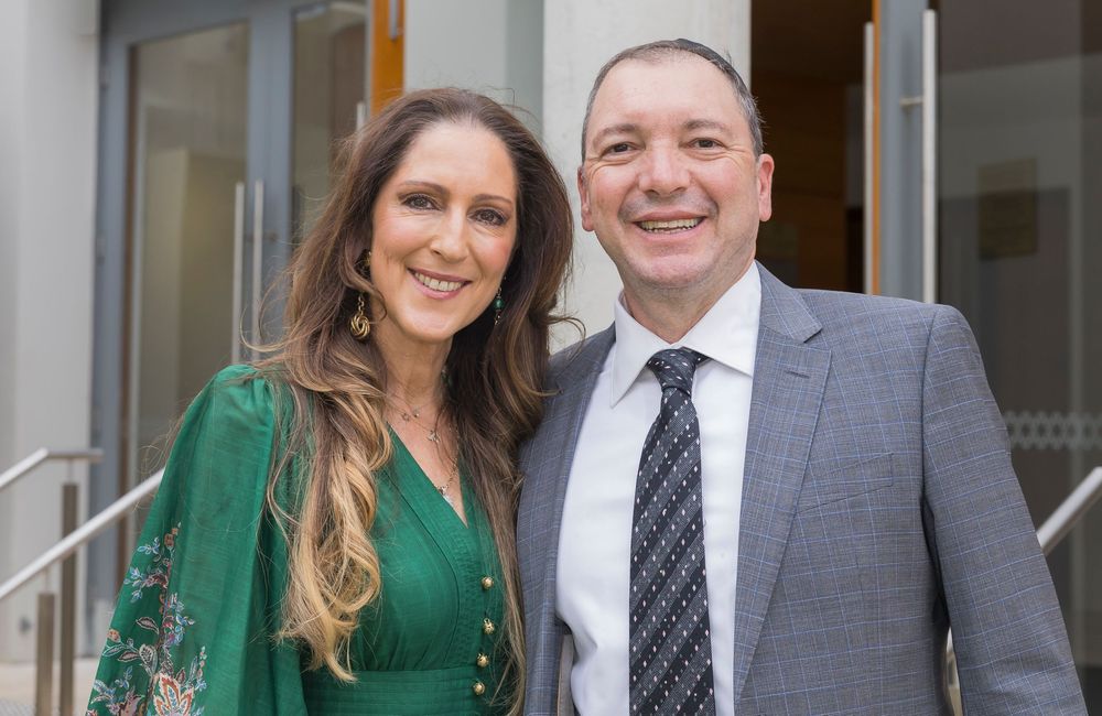 Two people in formal business attire stand together smiling at the camera.