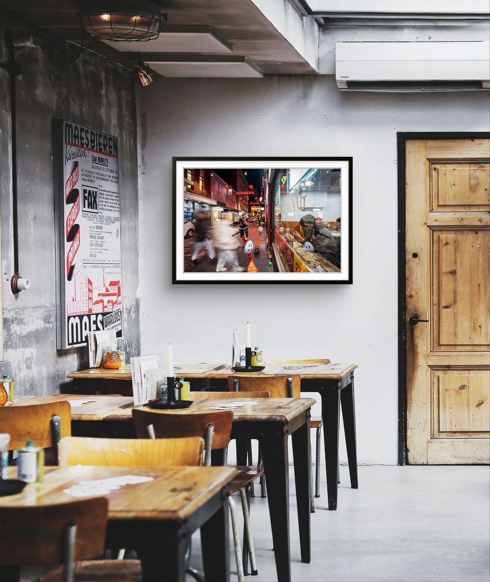 Black framed vibrant city street photography print hanging in a rustic industrial-style restaurant interior.