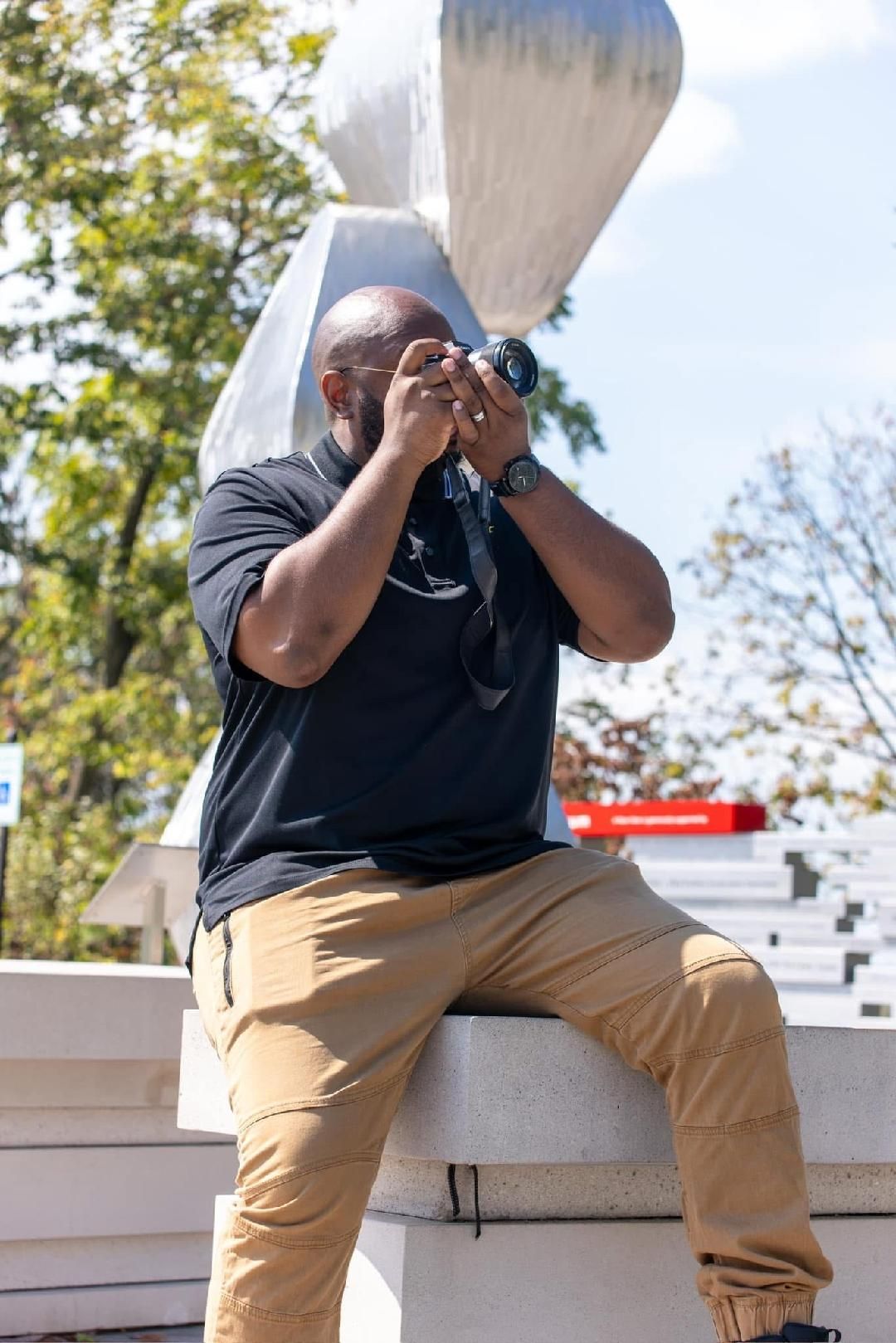 Casual outdoor photo sequence in black polo and khaki pants on white stone ledge.