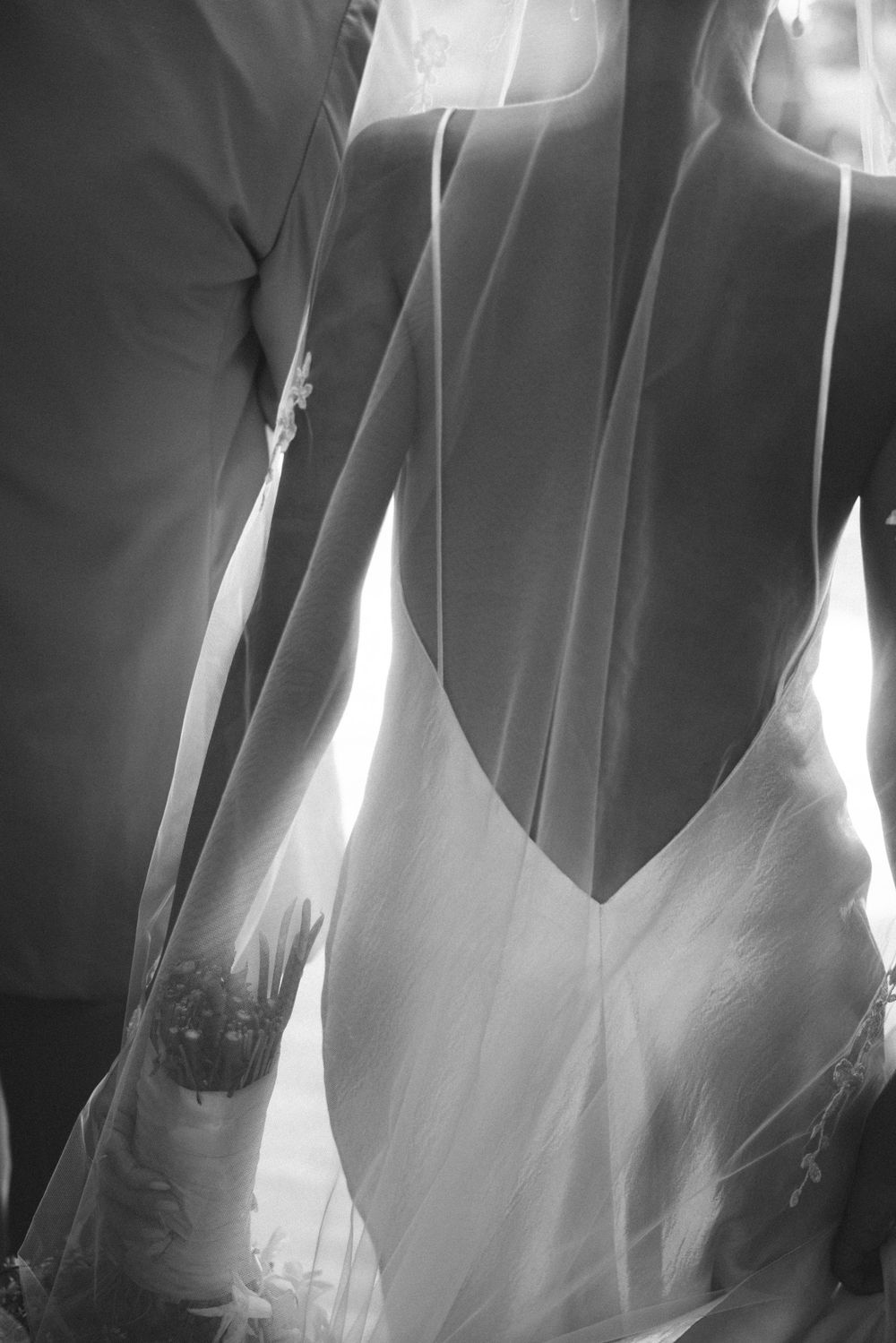 Close-up details of white wedding dresses hanging in a row showing delicate fabric textures.