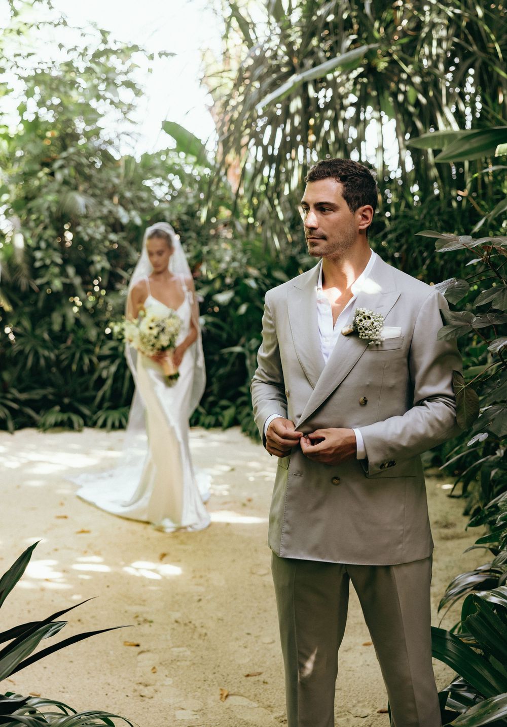 A wedding couple poses separately in a lush tropical garden setting.