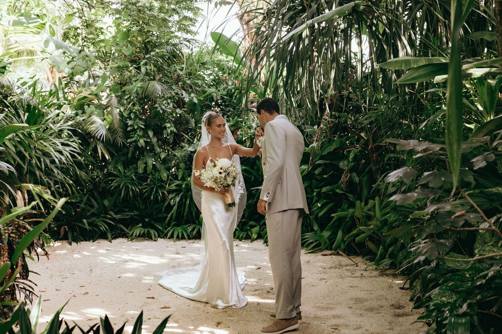 A wedding ceremony setup in a tropical garden pathway surrounded by palm trees.