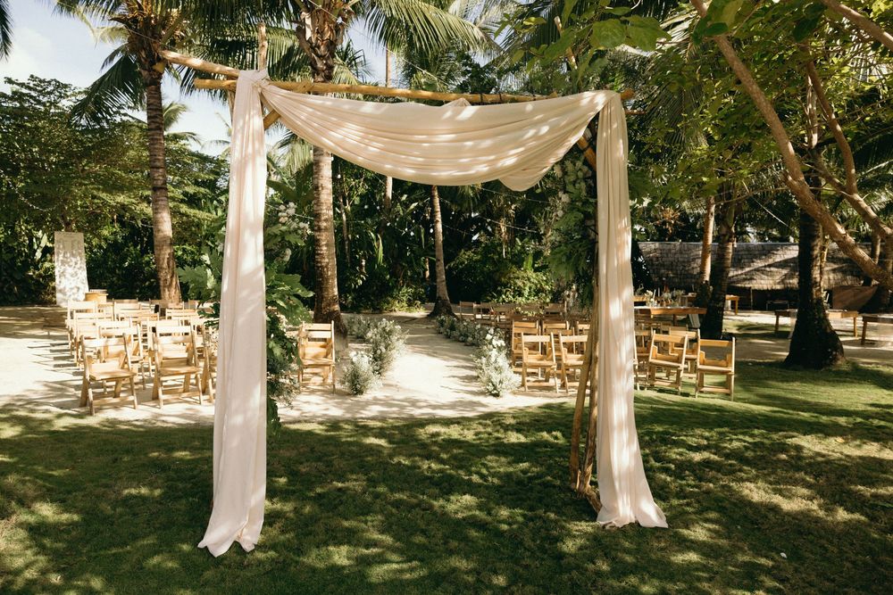 Elegant fabric canopy draped between palm trees for a tropical outdoor ceremony.