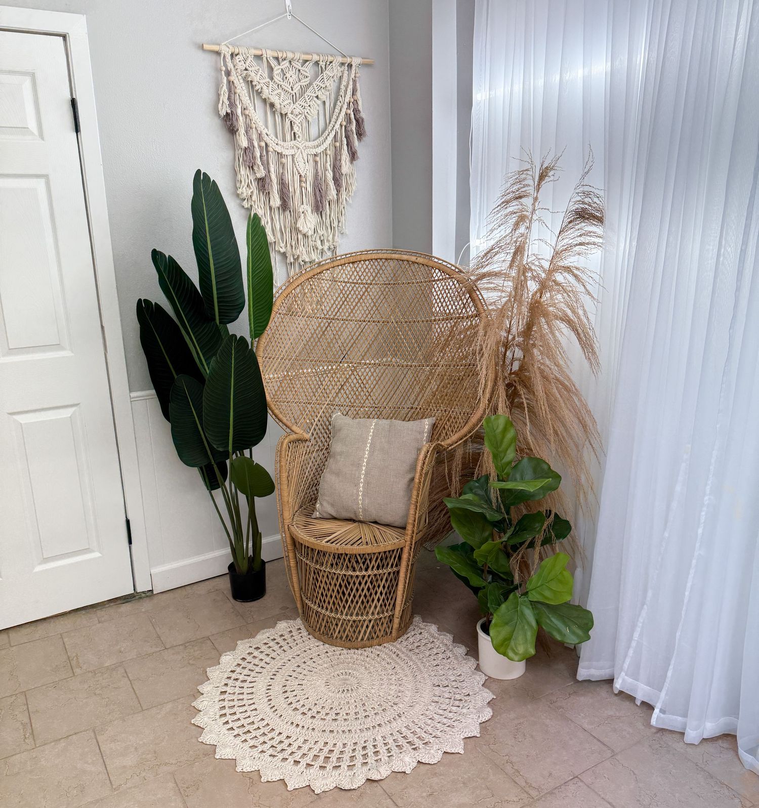 Boho-style corner with rattan chair, macrame wall hangings, white curtains, and potted plants on a tiled floor. Bismarck, ND