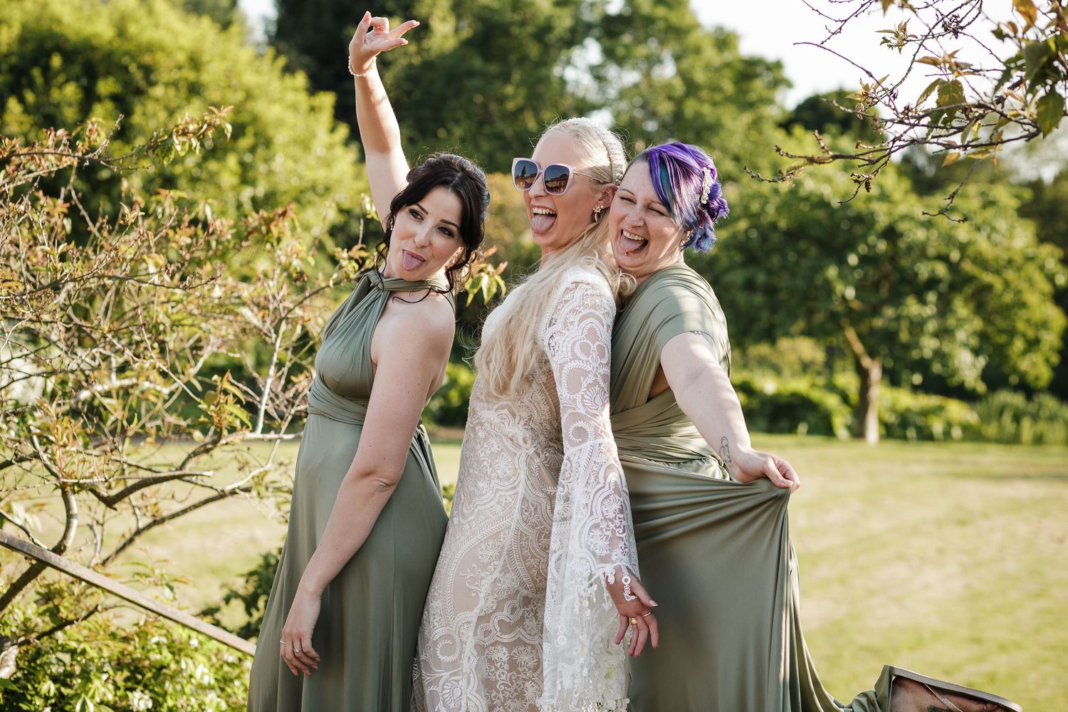 Bride and bridesmaids huddled together laughing outdoors at Hodsock Priory.