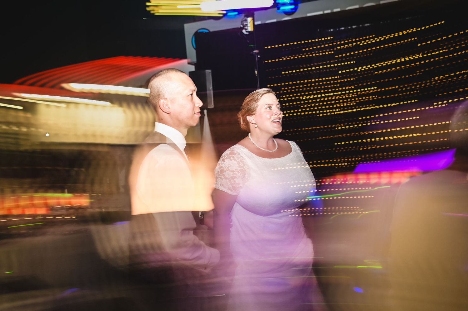 Couple standing at the Geo Centre on Signal Hill during their wedding reception, captured with slow-shutter light trails and moving lights