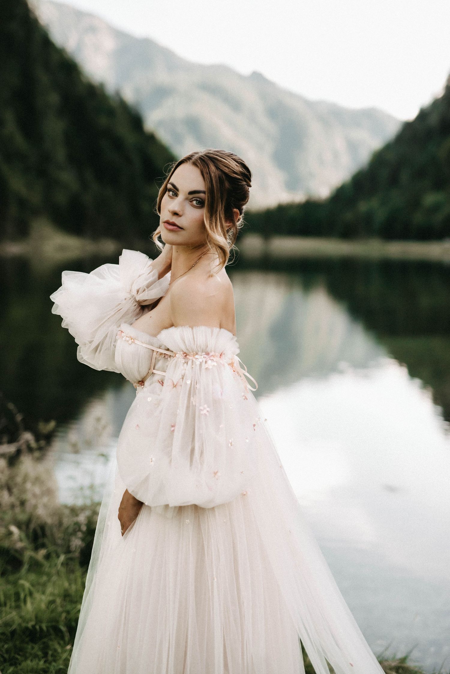 Dreamy bridal photos in a flowing white dress with mountain lake scenery.