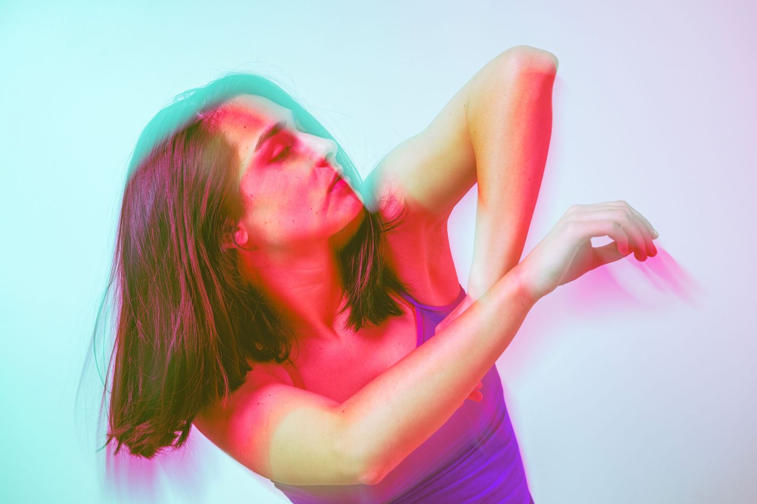 Person in a white top doing a plank exercise pose under dramatic blue lighting.