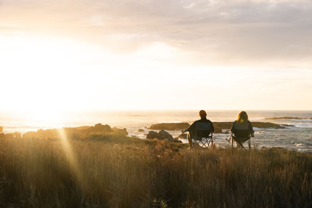 Scenic coastal sunset view with RV campers parked along cliffside overlooking the ocean.
