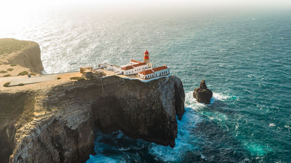 Dramatic aerial view of rugged coastline with turquoise waters and steep cliffs.