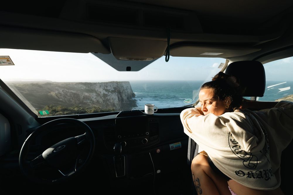 Interior view of a van showing someone resting in the passenger seat during a road trip.