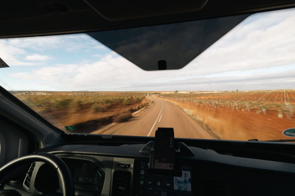 Dashboard view of driving through desert landscape with wide open roads.