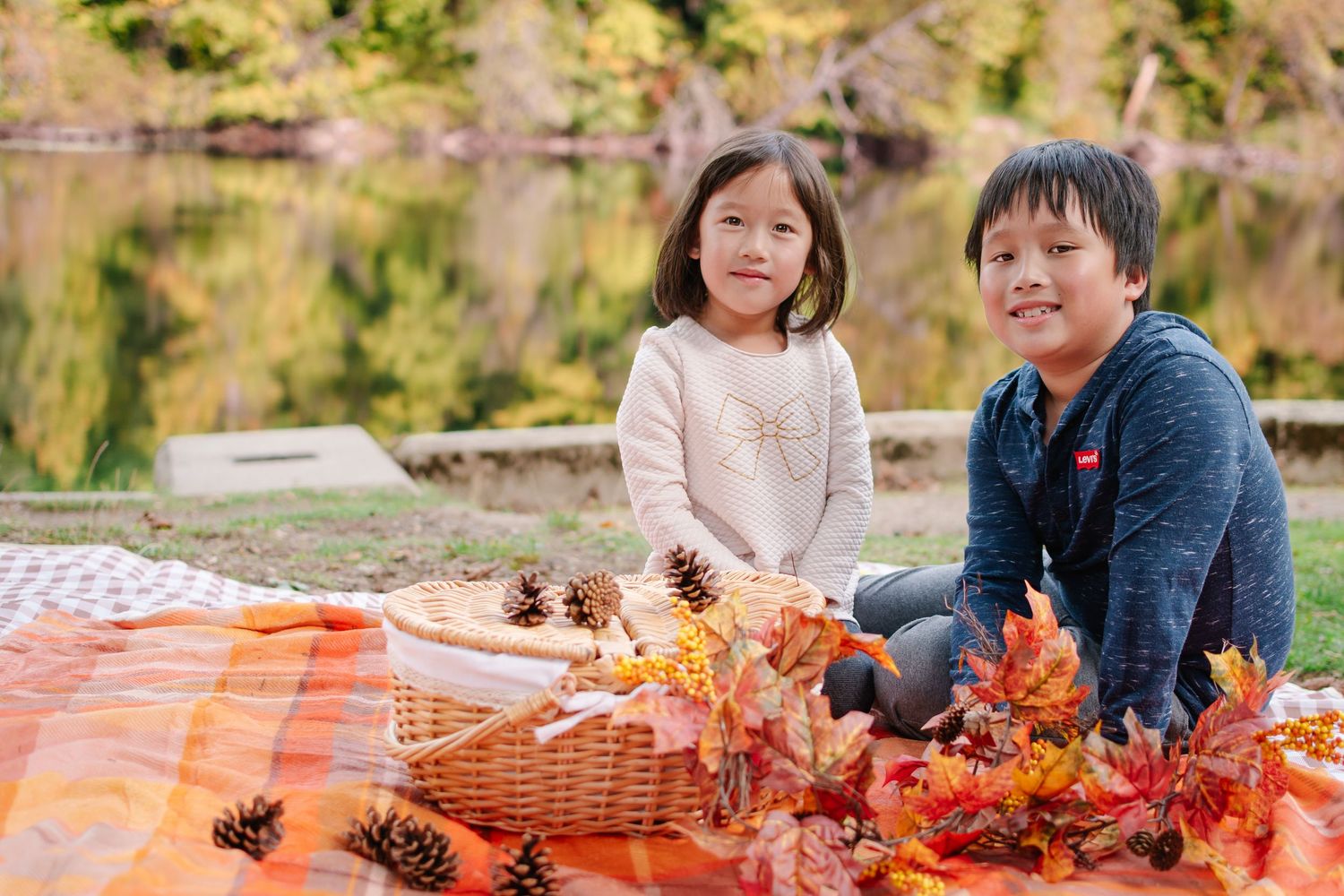 Children playing with fall leaves beside the lake at Lake Fenwick Park in Kent, WA.