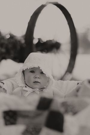 Black and white portrait showing a basket with patchwork quilt in natural lighting.