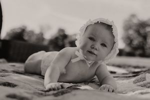 Outdoor portrait session featuring a patchwork quilt and wicker basket in natural sunlight.