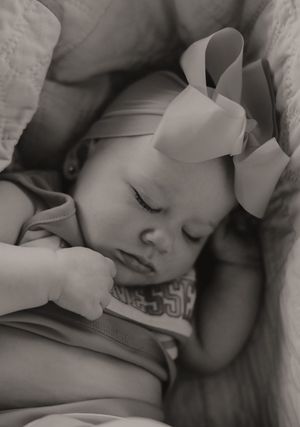 Black and white portrait of sleeping baby with bow.