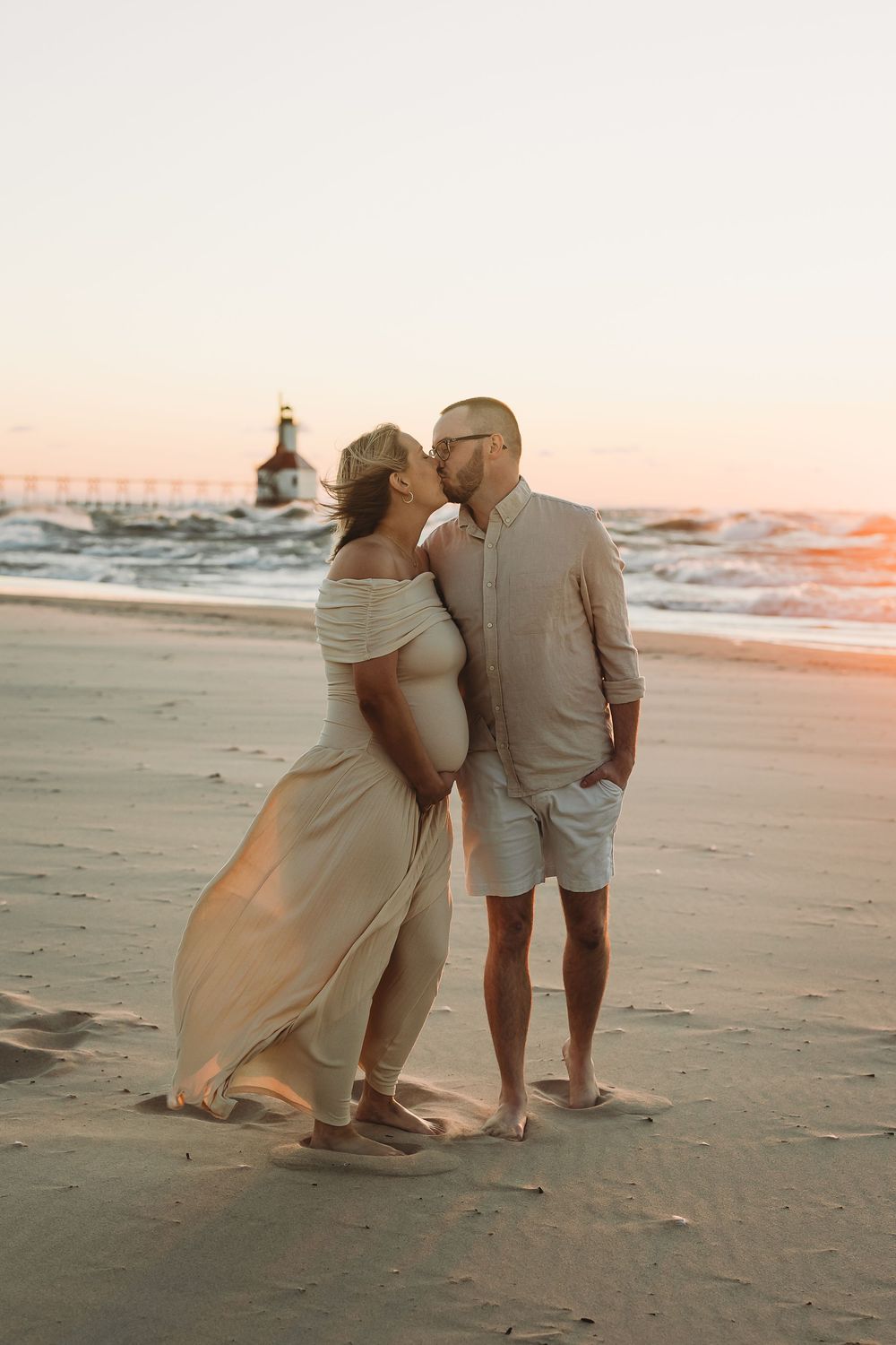A couple shares a romantic moment walking along the beach at sunset with waves crashing in the background.