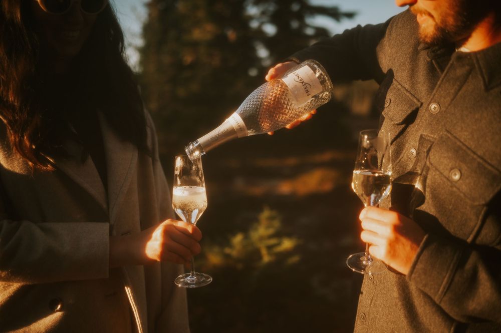 Film edit engagement fall adventure photoshoot on Mt. Washington of couple pouring champagne in Paradise Meadows Vancouver Island