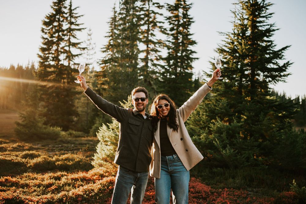 Engagement fall adventure photoshoot on Mt. Washington of couple celebrating with champagne in Paradise Meadows Vancouver Island