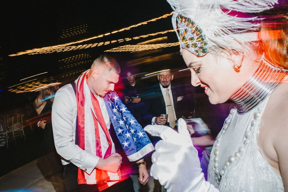 A group of people dancing and celebrating at a wedding reception with American flags and patriotic decorations.