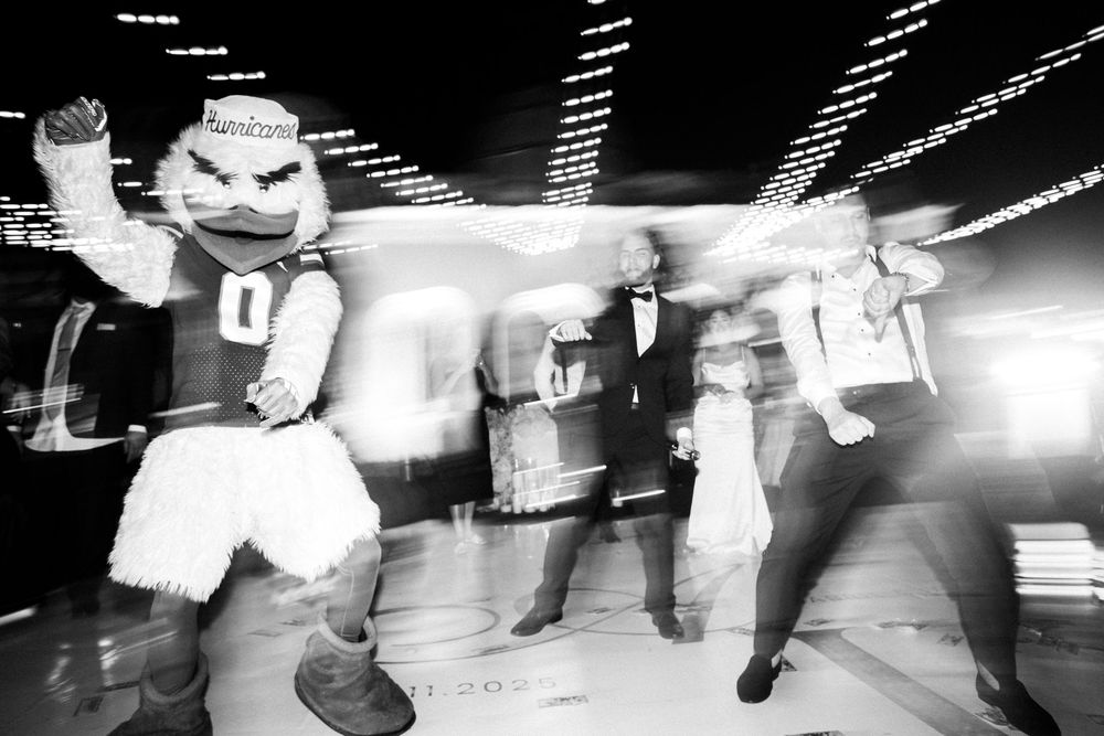 Black and white photo showing a mascot and two people dancing energetically at what appears to be a party or celebration.