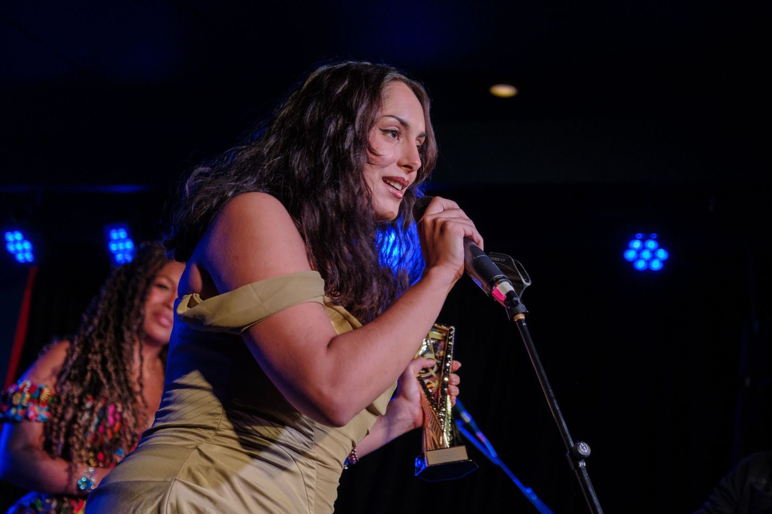 Singer performs on stage with blue stage lighting in the background during a live concert performance.