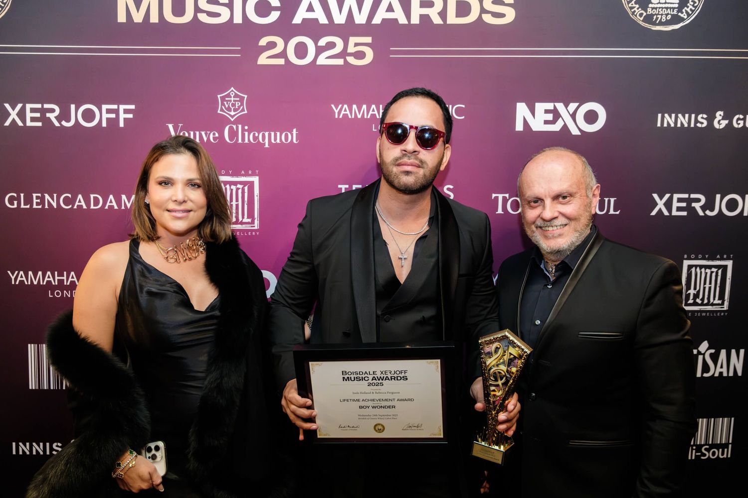 Music awards ceremony backdrop featuring sponsor logos and purple lighting at an entertainment industry event.