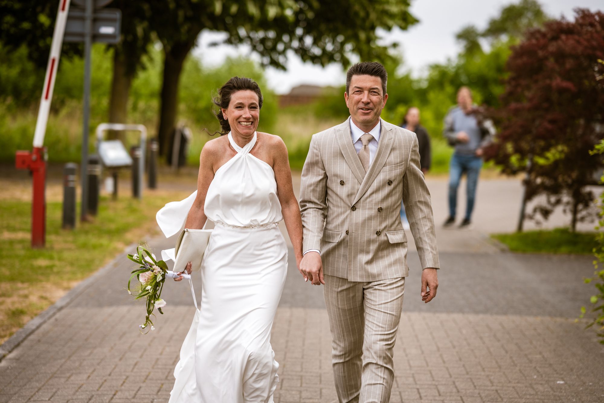 Trouwkoppel wandelt hand in hand in Hemiksem, vastgelegd door huwelijksfotograaf Bart Boodts Photography.
