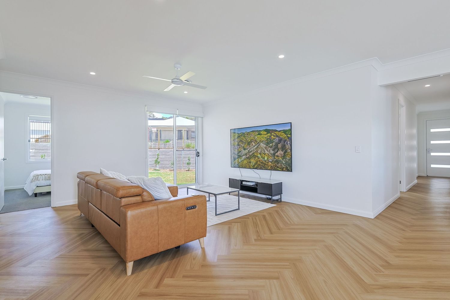 Bright modern living room with timber herringbone floors and neutral styling, photographed for real estate listing photography.