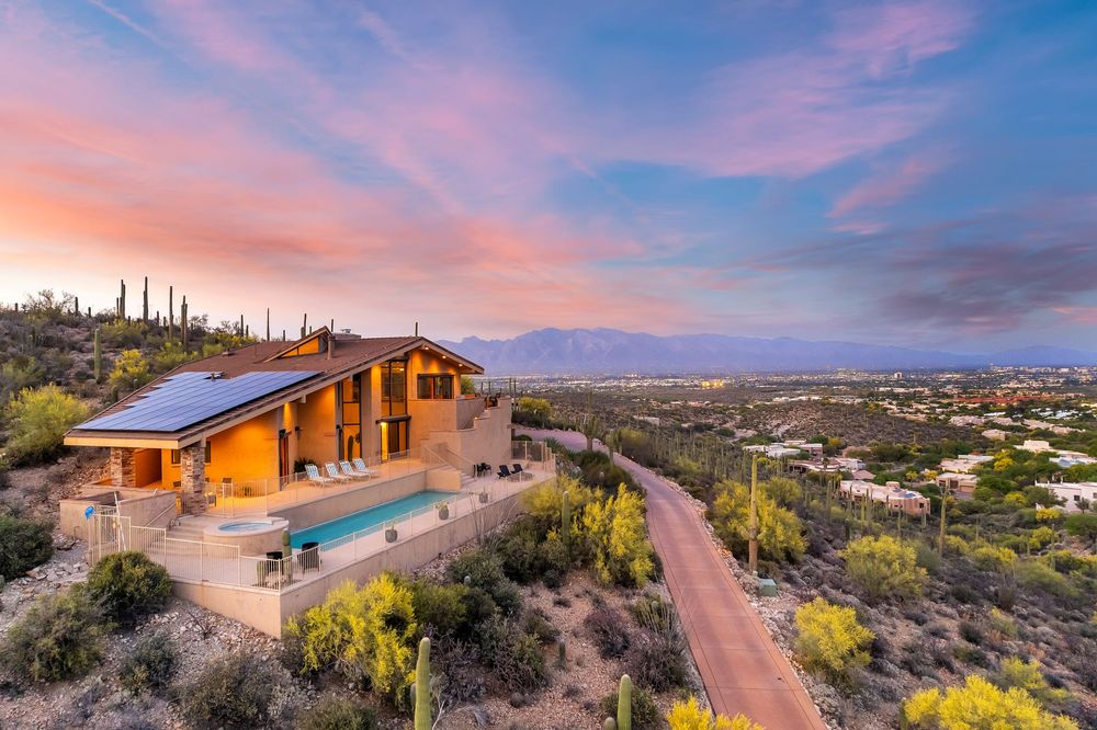 Scenic desert landscape with luxury homes nestled in the hills under a dramatic sunset sky.