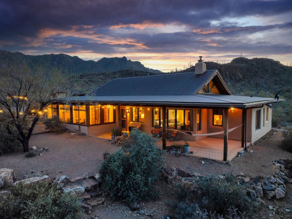 A panoramic view of a desert resort lodge at sunset with glowing windows and dramatic cloudy skies.