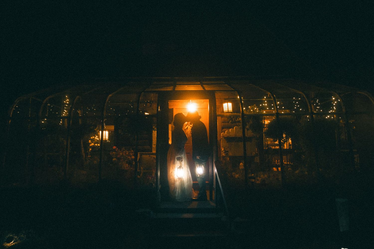 A dark nighttime scene with glowing street lamps illuminating trees and buildings in the background. inn at oxbow, Milan nh wedding